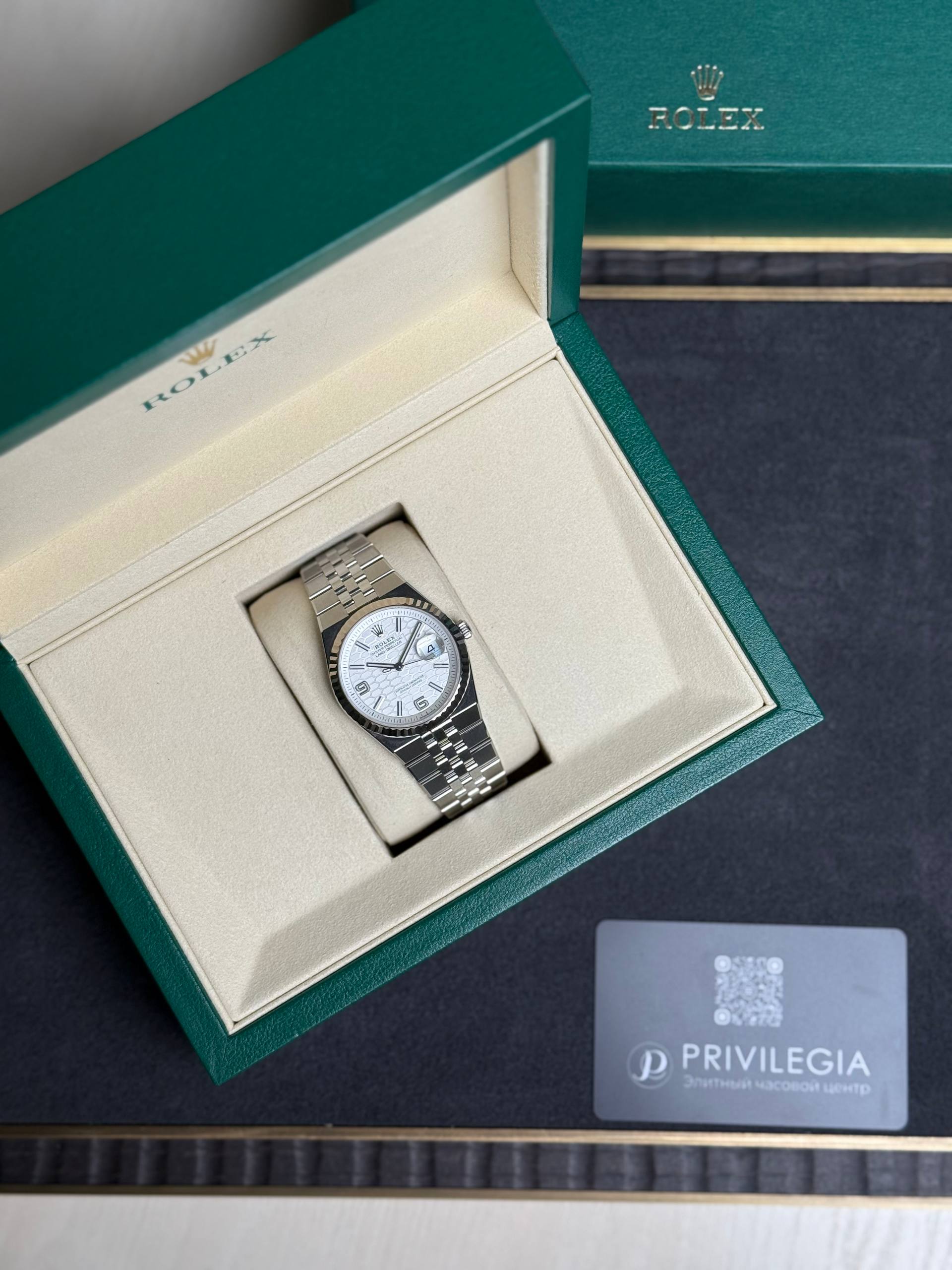 Rolex wristwatch in beige interior of green presentation box, partial view of outer box and a Privilegia card nearby