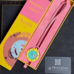 Pink Audemars Piguet x Swatch packaging with a yellow watch featuring a turquoise dial inside and a pink strap, plus a Privilege card nearby.