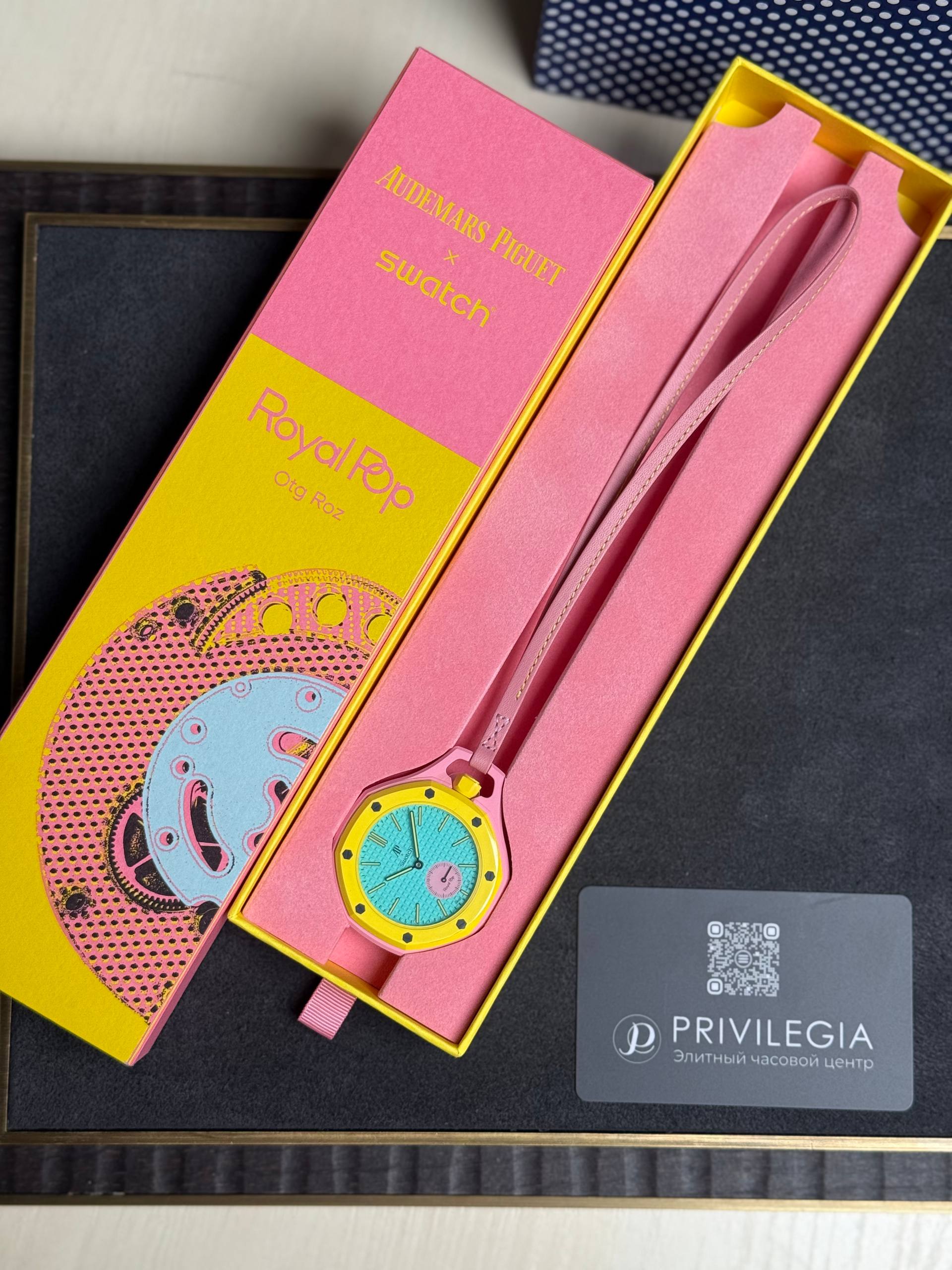 Pink Audemars Piguet x Swatch packaging with a yellow watch featuring a turquoise dial inside and a pink strap, plus a Privilege card nearby.