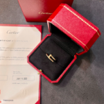 Gold ring in a red Cartier box on a display, with a certificate nearby.
