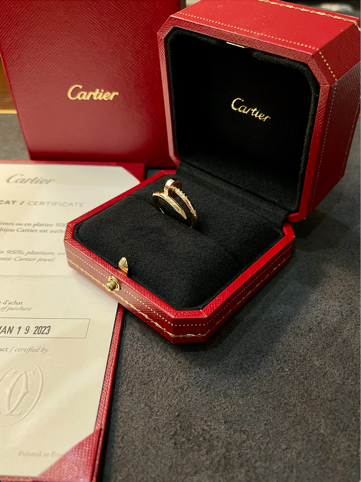 Gold Cartier ring in an open black velvet jewelry box with the Cartier logo, inside a red presentation box with stitching.